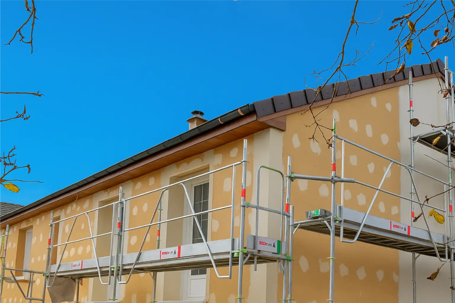 Façade de maison en cours d'isolation avec échafaudage et ciel bleu à Dijon